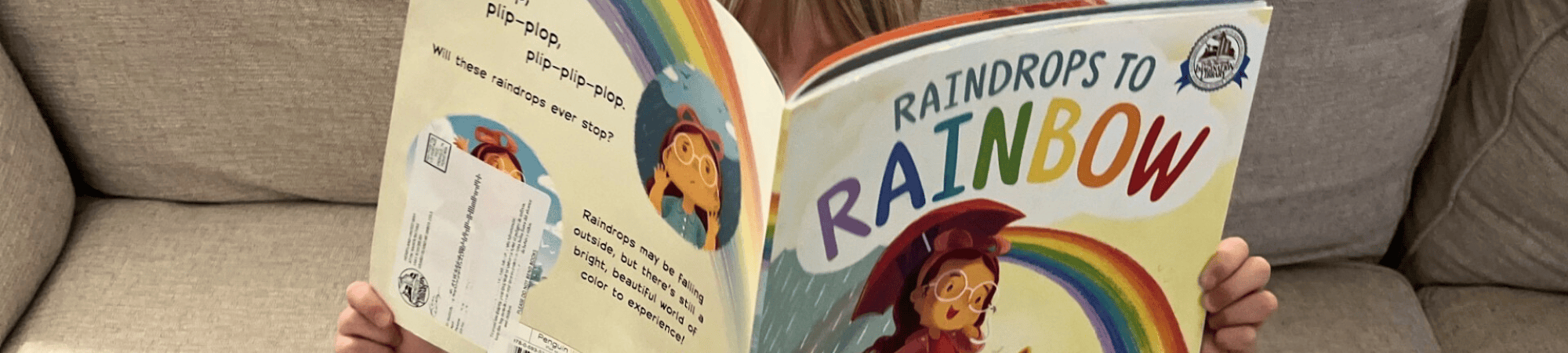 A girl reads the book "Raindrops to Rainbow" from Dolly Parton's Imagination Library