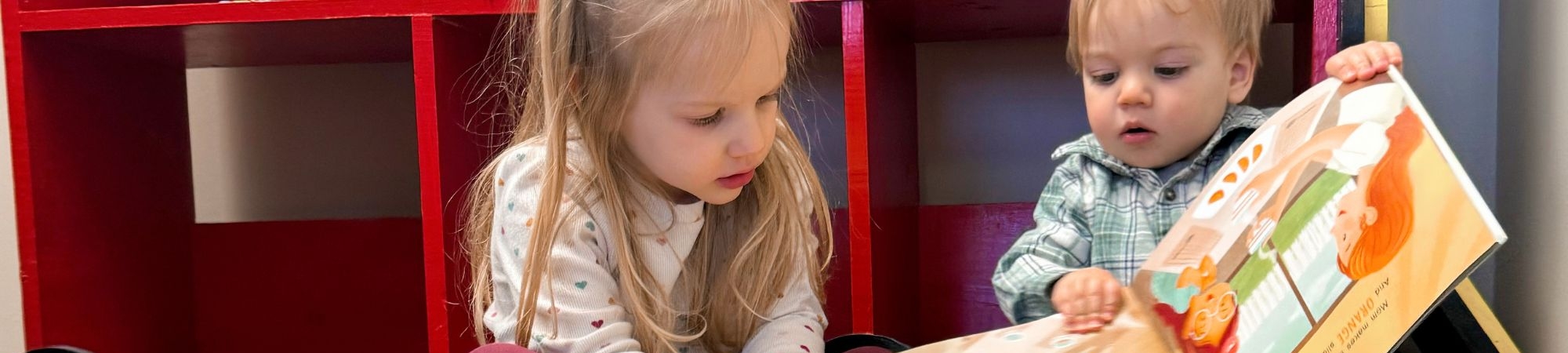 Small children read a book together.