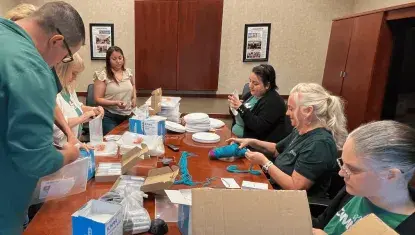First National Bank employees gather around a conference room table to assemble packets for local nonprofits during their own 2025 Day of Action.